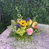 Colorful flower arrangement with a sunflower, pink blooms, and a butterfly pick in a low container