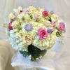 Bouquet of pale hydrangeas, pink roses, and white orchids in a glass vase