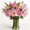 Pink roses and lilies arranged in a clear glass vase