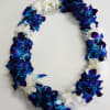 Lei of blue and purple orchids mixed with white blossoms in an oval shape