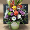 Mixed bouquet in a white vase with lilies, roses, and daisies
