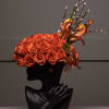 Orange rose arrangement in a black bust vase with pussy willow stems