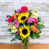 Mixed bouquet with sunflowers, pink and orange blooms in a glass vase