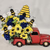 Yellow sunflowers and blue hydrangeas arranged in a red toy truck with bee decorations