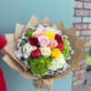 A vibrant hand-tied bouquet featuring a mix of pastel and bold roses