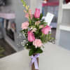 Bright pink roses, pale carnations and snapdragons with greenery in a glass