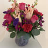 A vibrant and elegant arrangement featuring pink roses, soft peach lilies, purple