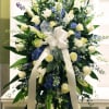 Tall white and blue floral standing spray with a ribbon bow