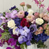 Mixed bouquet of roses, orchids, and hydrangeas in a white vase