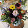 Mixed bouquet in a white vase with bright yellow, pink, red, and purple blooms