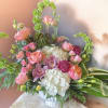 This arrangement has hydrangea, bells of Ireland, garden roses, lisianthus, Scabiosa, spray
