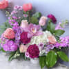 This arrangement has roses, hydrangea, stock, carnations, and orchid and greenery.