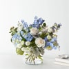 Pale blue hydrangea clusters and spiky delphinium mix with pure white roses