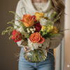 Mixed roses in a round glass vase with airy greenery