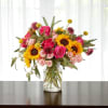 Bouquet of sunflowers and pink roses in a clear glass vase