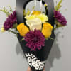 Bright yellow roses and sculptural white calla lilies pop against saturated purple