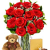 Bouquet of red roses in a glass vase with a teddy bear and chocolates
