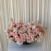 A low, rounded cascade of pale pink and blush pink roses arranged