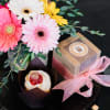 Bouquet of pink, white, and yellow gerbera daisies with a dessert box and pastry