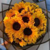 Bouquet of bright yellow sunflowers wrapped in dark paper