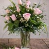 Pink roses arranged in a clear glass vase with mixed greenery.