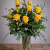 Yellow roses arranged in a clear glass vase with greenery