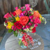 Mixed bouquet of roses and bright flowers in a glass vase