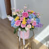 Colorful mixed bouquet in a pink hatbox on a gold stand