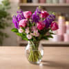 A burst of pink roses and tall purple blooms makes this flower