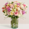 Mixed pastel bouquet of roses and lilies in a clear glass vase
