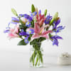 Bouquet of pink lilies and purple irises in a clear glass vase