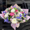 Bouquet of pink, white, and blue flowers wrapped in pink paper