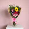 Mixed bouquet with pink and yellow flowers wrapped in clear paper