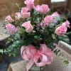 Pink roses in a glass vase with a pink ribbon bow