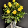 Yellow roses arranged in a white vase with a black-and-white ribbon