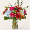 Mixed bouquet of roses, lilies, and hydrangeas in a clear glass vase