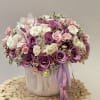 Pink and white rose arrangement in a ceramic vase with a ribbon