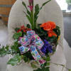 Mixed flower basket with pink calla lilies, orange blooms, and a floral ribbon