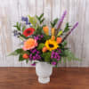 A burst of sunlit color-bright yellow sunflowers with coral roses, orange tulips