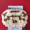 Boxed arrangement of cream and brown roses against a red background