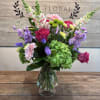 Bright pink roses and vivid gerbera daisies anchor this Secret Garden flower