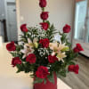 Red roses and pale lilies arranged in a red hatbox