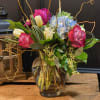 Mixed bouquet of pink, white, and blue flowers in a glass vase