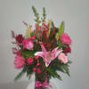 Pink and red floral arrangement in a glass vase with a pink ribbon