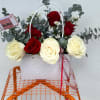 Basket arrangement of red and white roses with eucalyptus and a small card