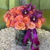 Bouquet of orange-pink roses and purple orchids in a glass vase