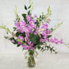 Pink and white orchids arranged in a clear glass vase.