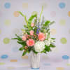 Pink gerberas and roses in a white vase with white hydrangea and tall greenery
