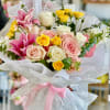 Bouquet of pink, white, and yellow roses with lilies wrapped in lace paper