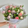 A round bouquet of white and pink flowers with lush greenery, wrapped